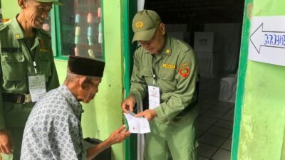 Petugas keamanan TPS 5 Desa Warnasari Kabupaten Sukabumi membantu salahsatu warga yang akan melakukan pemungutan suara ulang Pilkada Kabupaten Sukabumi 2024 pada Minggu 1 Desember 2024. FOTO: Heryadie/HALOSMI