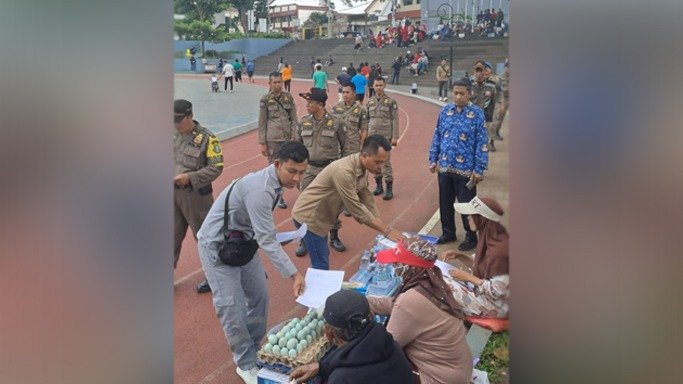 Petugas gabungan memberikan surat himbauan kepada penyewa sepeda listrik, mobil-mobilan listrik, otopet listrik, trampolin, mandi bola hingga pedagang di Lapang Merdeka Kota Sukabumi. Foto: Istimewa.
