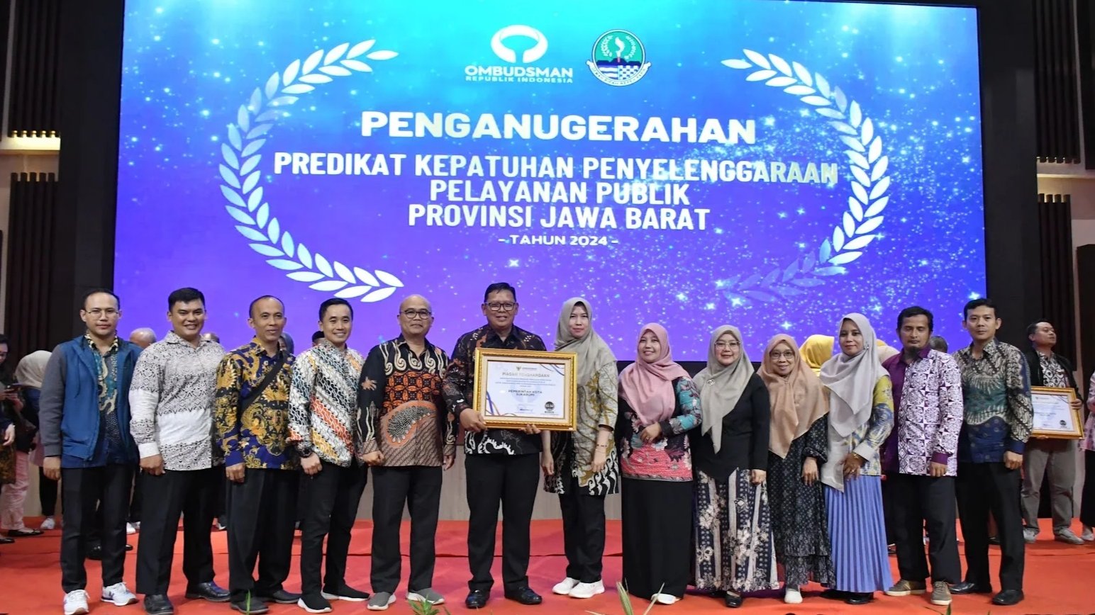 Pj Wali Kota Sukabumi, Kusmana Hartadji, menerima penganugerahan kepatuhan penyelenggaraan pelayanan publik dari Ombudsman di Grand Sunshine Resort and Convention, Bandung. Foto: Dokpim Kota Sukabumi.